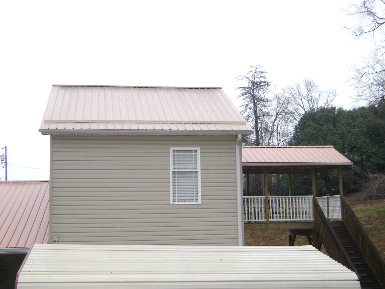 Tan metal roofs on a two story addition and attached porch, from a Roof Replacement job in Hanover